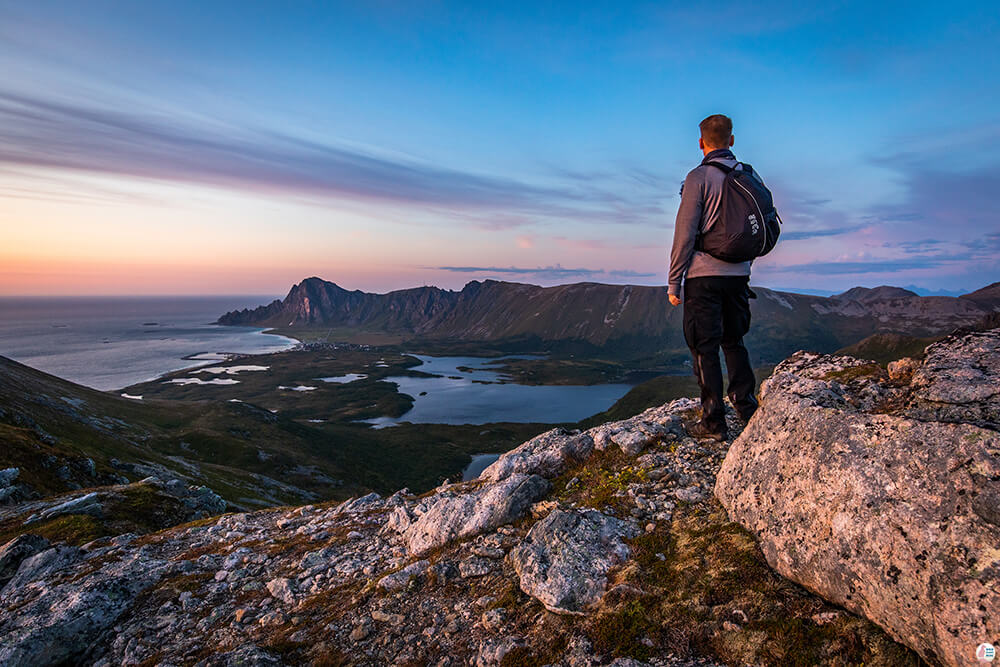 Hiker admiring sunset over Bleik village, Måtind, Andøya, Northern Norway