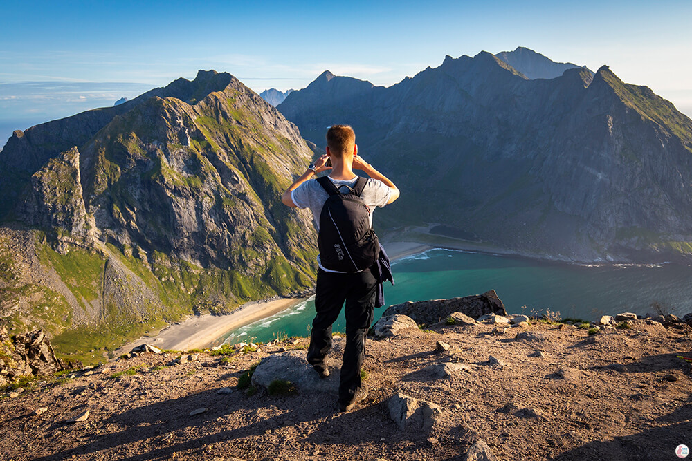 Tourist taking picture at Kvalvika beach viewpoint, Ryten hiking trail, Moskenesøya, Lofoten, Norway